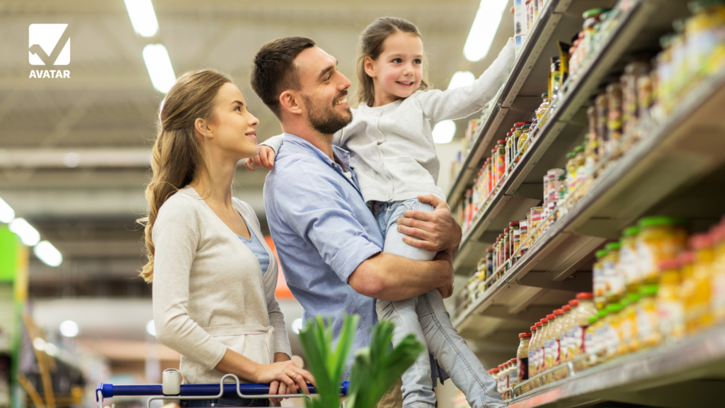 A family shopping in a grocery store. The father holds a young girl reaching for an item on a high shelf, while the mother stands with a shopping cart. This image highlights practical math skills like calculating discounts, budgeting, and comparing prices in everyday life.
